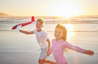 孩子们运行<strong>飞机玩具</strong>海滩健康锻炼健康的发展日落地平线海洋波孩子们有趣的玩户外夏天假期肖像
