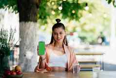 年轻的女人持有智能手机绿色屏幕