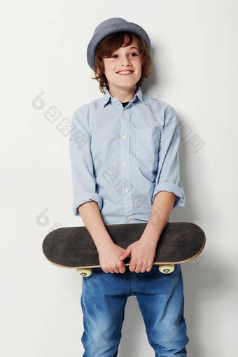 <strong>潮流引领</strong>者轮子可爱的13岁以下的男孩穿时尚的服装持有滑板孤立的白色