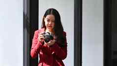 漂亮的年轻的亚洲女人摄影师检查图片相机站窗口