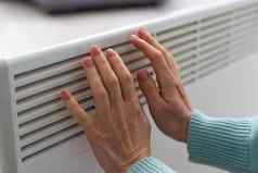 女人的手白色散热器加热季节能源危机冷电池中央加热