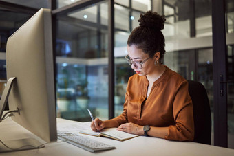 女人晚上办公室写作电脑规划业务的想法时间表策略启动公司焦点员工笔记本时间表桌面信息报告黑暗工作场所