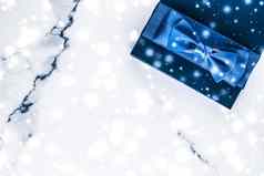 冬天假期礼物盒子蓝色的丝绸弓雪闪闪发光的大理石背景圣诞节年礼物奢侈品美品牌平铺设计