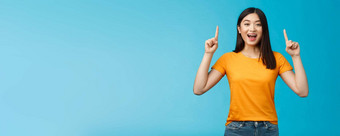 逗乐亚洲女孩介绍产品分享促销提高手指出手指微笑广泛的兴奋乐观的热情的广告站蓝色的背景
