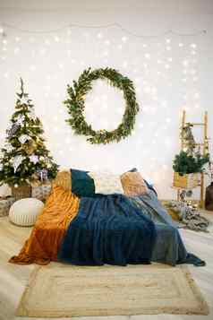 圣诞节节日室内灰色的白色颜色轮绿色花环挂起墙床上覆盖舒适的毯子站房子装饰加兰