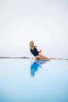 年轻的美丽的女人泳衣坐在池涂片皮肤防晒霜护肤品夏天