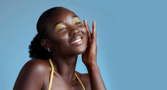 黄色的化妆黑色的女人脸美护肤品化妆品产品蓝色的工作室墙思考考虑沉思的非洲女孩感觉软皮肤纹理眼影模型
