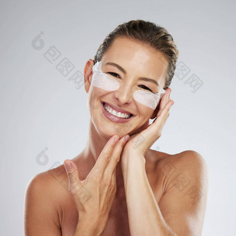 女人美护肤品眼睛补丁化妆品化妆脸产品石油问题灰色的工作室背景女肖像面部反老化眼睛治疗皱纹健康的胶原蛋白