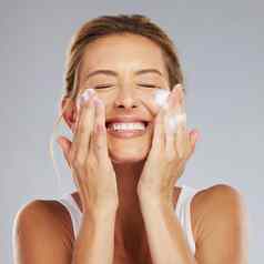 脸清洁卫生成熟的女人洗皮肤工作室灰色的背景护肤品医疗保健美女保持头清洁新鲜的卫生例程