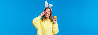 假期传统庆祝活动概念快乐快乐的年轻的漂亮的女庆祝复活节一天显示画鸡蛋笑穿可爱的兔子耳朵蓝色的背景