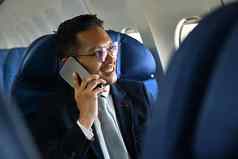积极的商人西装会说话的移动电话坐着舒适的座位飞机小屋