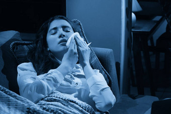 年轻<strong>的</strong>女人沙发覆盖毯子冻结吹运行鼻子发热抓住了生病<strong>的</strong>女孩流感症状流感病毒概念