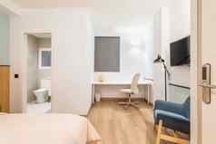 视图卧室大床上工作区域白色木表格舒适的皮革办公室椅子小私人浴室开放通过一边舒适的扶手椅地板上灯