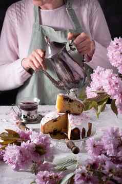 女人倒茶银茶壶背景粉红色的樱花花复活节
