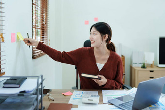 肖像深思熟虑的亚洲女商人金融语句使市场营销计划电脑笔记本桌子上