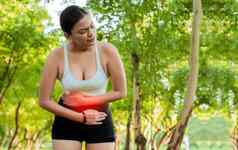 女人运动服装胃疼痛公园运行女人消化问题体育运动女孩胃疼痛在户外复制空间疲劳年轻的女人胃疼痛