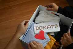 前视图年轻的志愿者持有盒子衣服捐赠刻字慈善机构捐赠重用回收概念