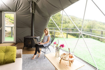 女人工作移动PC地理圆顶帐篷绿色蓝色的背景舒适的野营豪华露营假期假期生活方式概念在户外小屋风景优美的背景