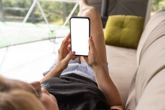 快乐年轻的高加索人女人放松舒适的沙发上首页发短信消息传递智能手机手机浏览无线互联网小工具购物在线首页