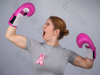女人<strong>粉</strong>红色的丝带胸部提出了手<strong>粉</strong>红色的拳击手套灰色的背景胜利乳房癌症