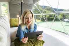 女人平板电脑圆顶帐篷豪华露营假期生活方式概念