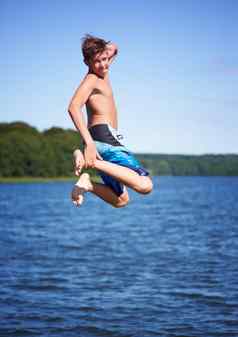 采取跳水年轻的的家伙半空中明亮的蓝色的天空跳跃湖