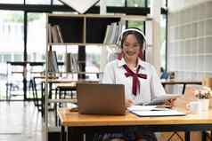 年轻的女人享受自主学习在线教育工具明亮的学生写作笔记本移动PC电脑电子学习看网络研讨会参加e级