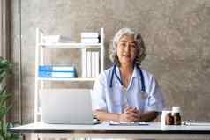 肖像高级头发灰白的女医生办公室移动PC视频闲谈，聊天病人在线咨询医生诊断治疗建议