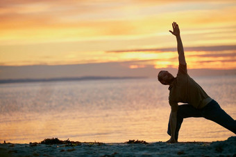 拉伸身体拉伸心男人。练习三角形构成瑜伽例程海滩