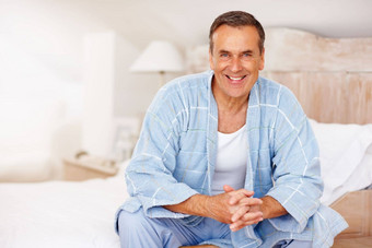微笑成熟的男人。浴袍坐着床上首页肖像微笑成熟的男人。浴袍坐着床上首页