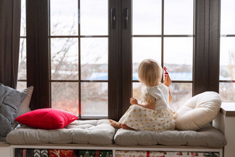 女孩年坐在窗台上金发女郎女孩白色衣服窗台上窗口持有糖果手