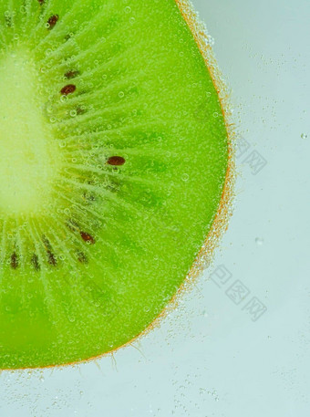 特写镜头猕猴桃水果液体泡沫片绿色成熟的猕猴桃水果闪闪发光的水多汁的猕猴桃水果碳酸水宏垂直图像