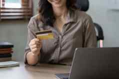 年轻的女人持有信贷卡女商人工作首页在线购物电子商务互联网银行支出钱工作首页概念