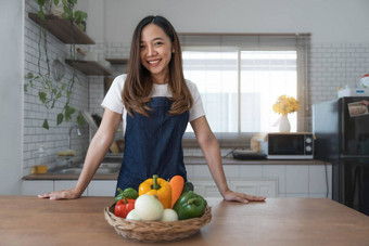 肖像年轻的快乐女人穿appron站厨房房间准备烹饪健康的食物新鲜的<strong>蔬菜水果</strong>