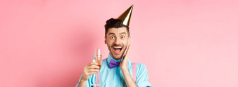 假期庆祝活动概念有趣的年轻的男人。生日他庆祝尖叫快乐惊喜提高玻璃香槟微笑站粉红色的背景
