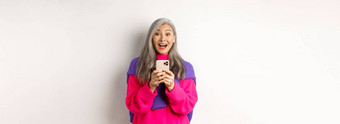 惊讶亚洲女人微笑相机阅读促销活动智能手机站移动电话白色背景