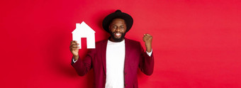 真正的房地产快乐的黑色的男人。欢乐显示纸首页模型站红色的背景