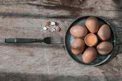 作文破碎的新鲜的鸡蛋母鸡蛋把中间新鲜的鸡蛋棕色（的）蛋壳黑色的古董银叉乡村木表格