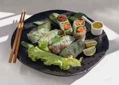 健康的越南春天卷部分的东西蔬菜服务辣的酱汁木筷子黑色的陶瓷板