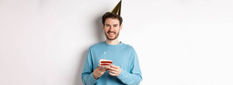 庆祝活动假期概念快乐年轻的男人。聚会，派对他庆祝生日持有bday蛋糕微笑站白色背景