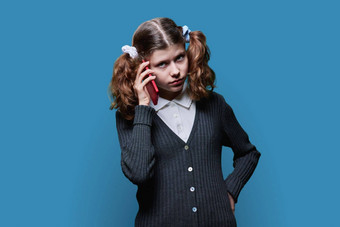 13岁以下的女<strong>学生会</strong>说话的移动电话蓝色的工作室背景