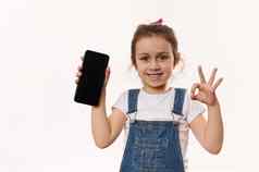 可爱的女孩持有细胞电话空白屏幕复制空间促销文本微笑显示标志相机