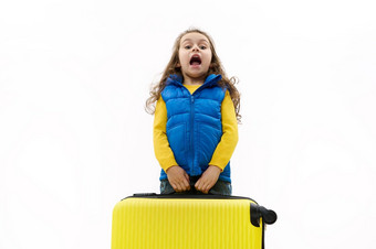 淘气的孩子旅行者女孩持有重黄色的手提箱表达惊喜白色背景复制空间