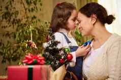 快乐女人爱的妈妈。女儿享受在一起拥抱装修圣诞节树