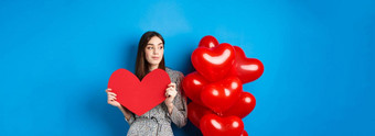 情人节一天浪漫的女孩衣服站气球持有大红色的心断路梦想站蓝色的背景