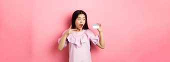 兴奋亚洲女人指出塑料信贷卡显示太棒了广告