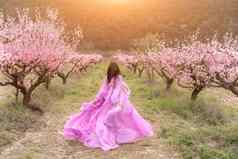 女人长粉红色的衣服走公园桃子果园大盛开的桃子果园
