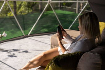 快乐年轻的高加索人女人放松舒适的沙发上首页发短信消息传递智能手机手机浏览无线互联网小工具购物在线首页