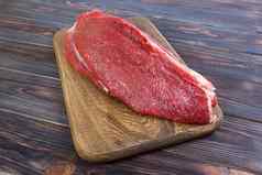 红色的新鲜的生牛肉小牛肉角切割董事会黑色的木背景