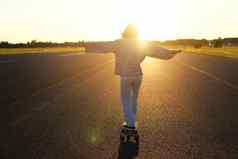 无忧无虑的青少年溜冰者女孩骑滑板手传播横盘整理滑冰太阳